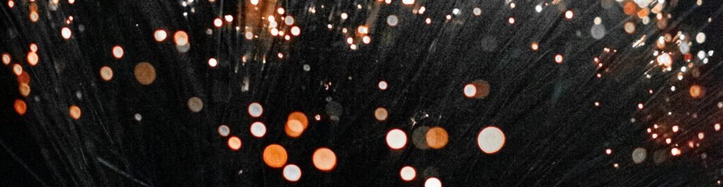 An artistic shot of fiber optic lights on a dark background creating a bokeh effect with vivid colors.