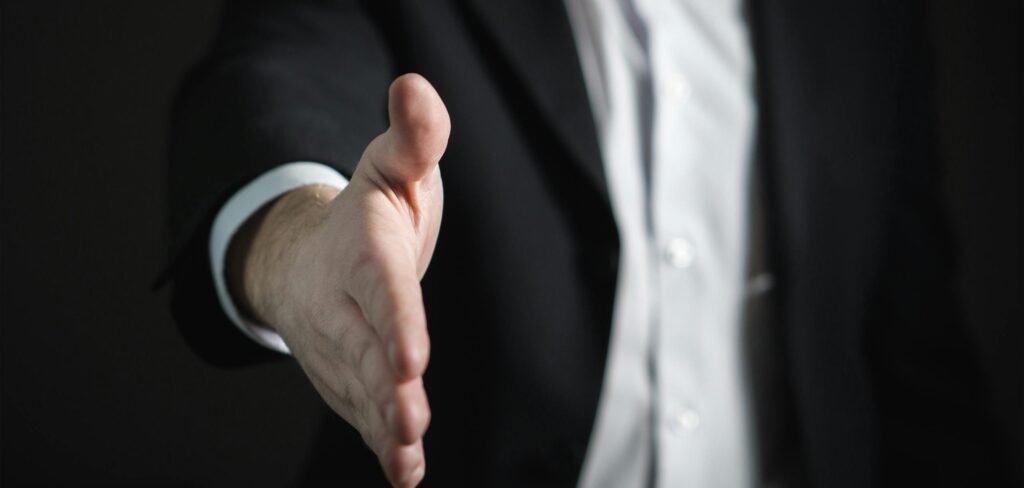 Close-up of a businessman extending hand for a handshake, symbolizing agreement and partnership.