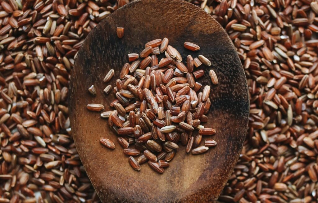 Close-up of a wooden spoon filled with raw brown rice grains, ideal for food and nutrition concepts.