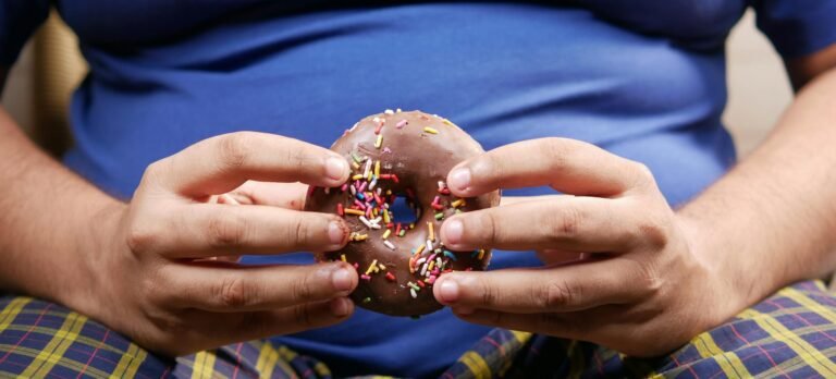 Close-up of hands holding a chocolate donut with colorful sprinkles. Perfect for dessert lovers.