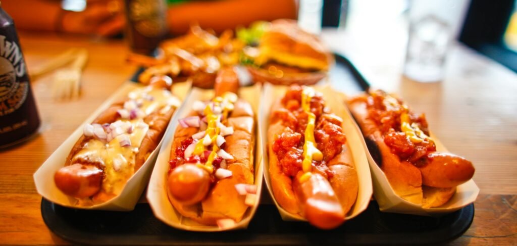 Close-up of various hotdogs with toppings on a wooden table, ideal for fast food themes.