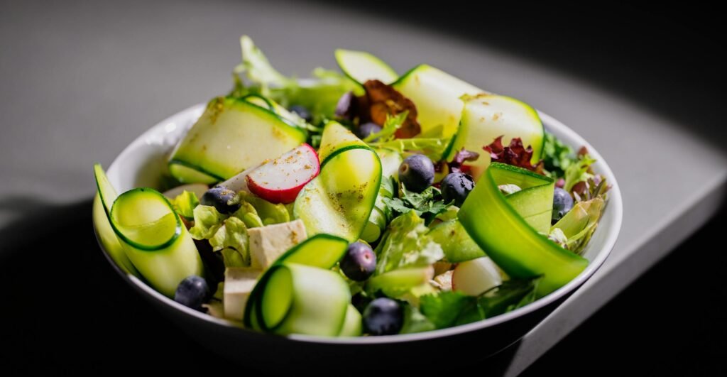 Delicious fresh salad with zucchini ribbons, radish, blueberries, and feta cheese, perfect for a healthy meal.