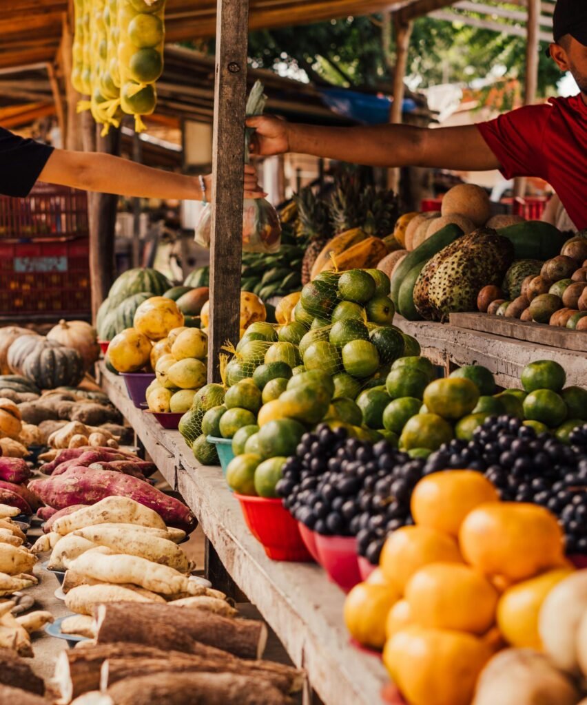 Diverse fruits and vegetables on display at a bustling outdoor market.