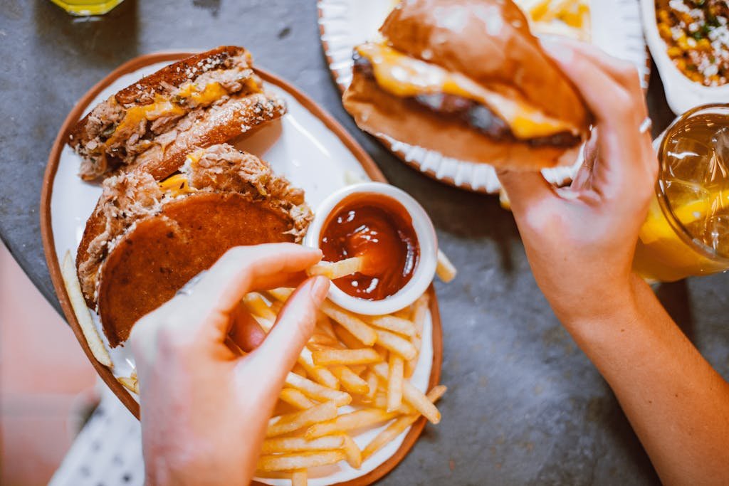 Fast food meal featuring burgers, fries, sauce and drinks.