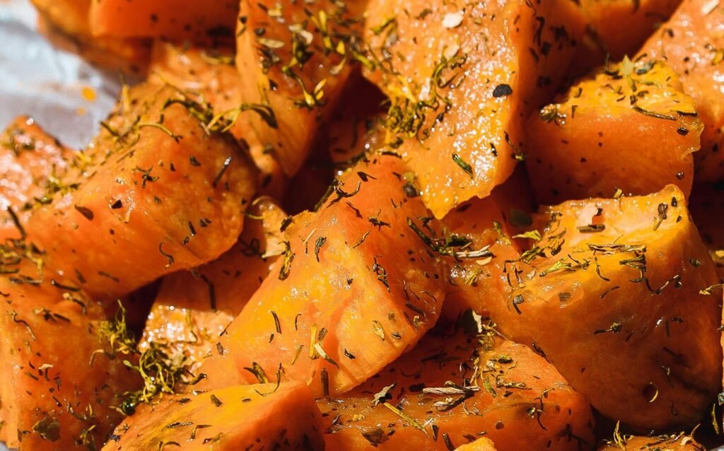 Close-up of delicious baked sweet potatoes seasoned with herbs, perfect for a healthy meal.