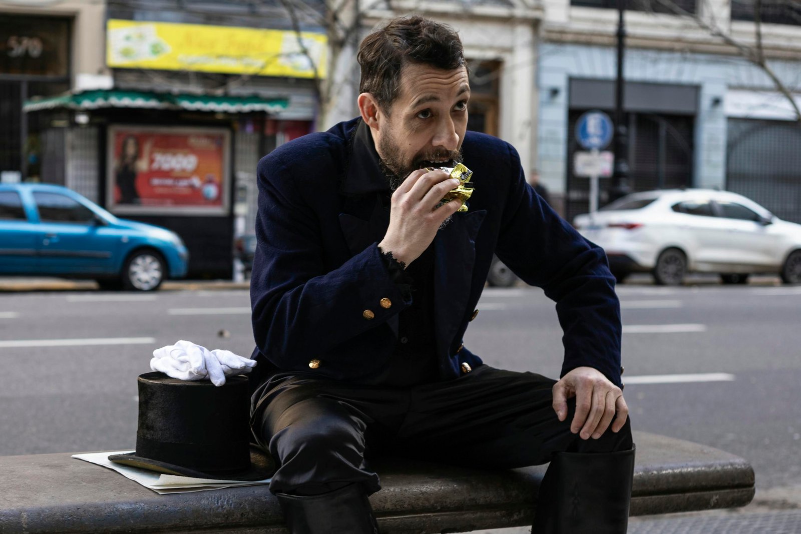 Gentleman in classic clothing enjoys a snack on a busy Buenos Aires street.