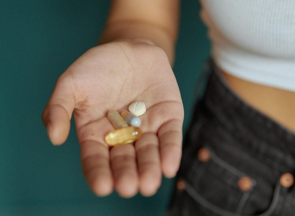 Person's hand holding different pills, highlighting medication and health care.